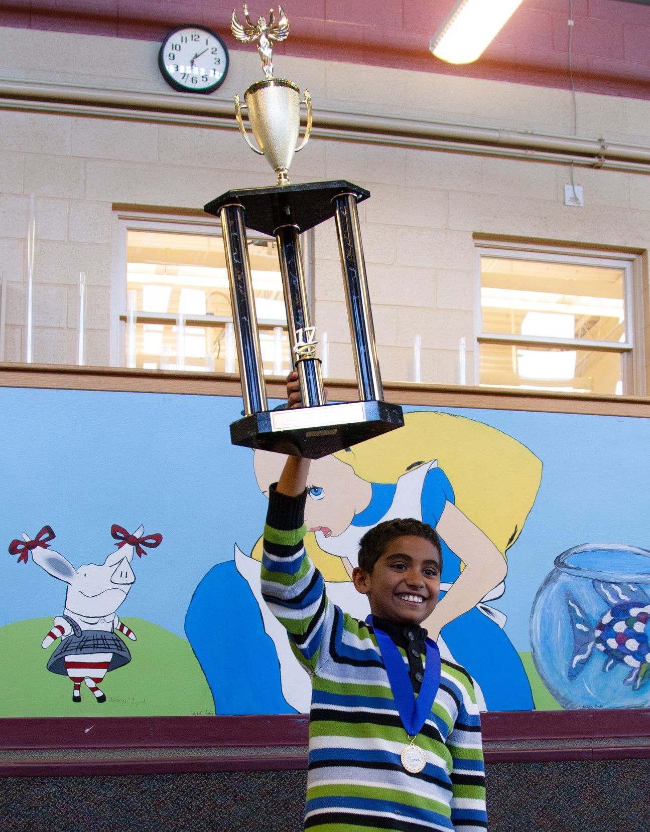 A student lifting a Stock Market Game trophy