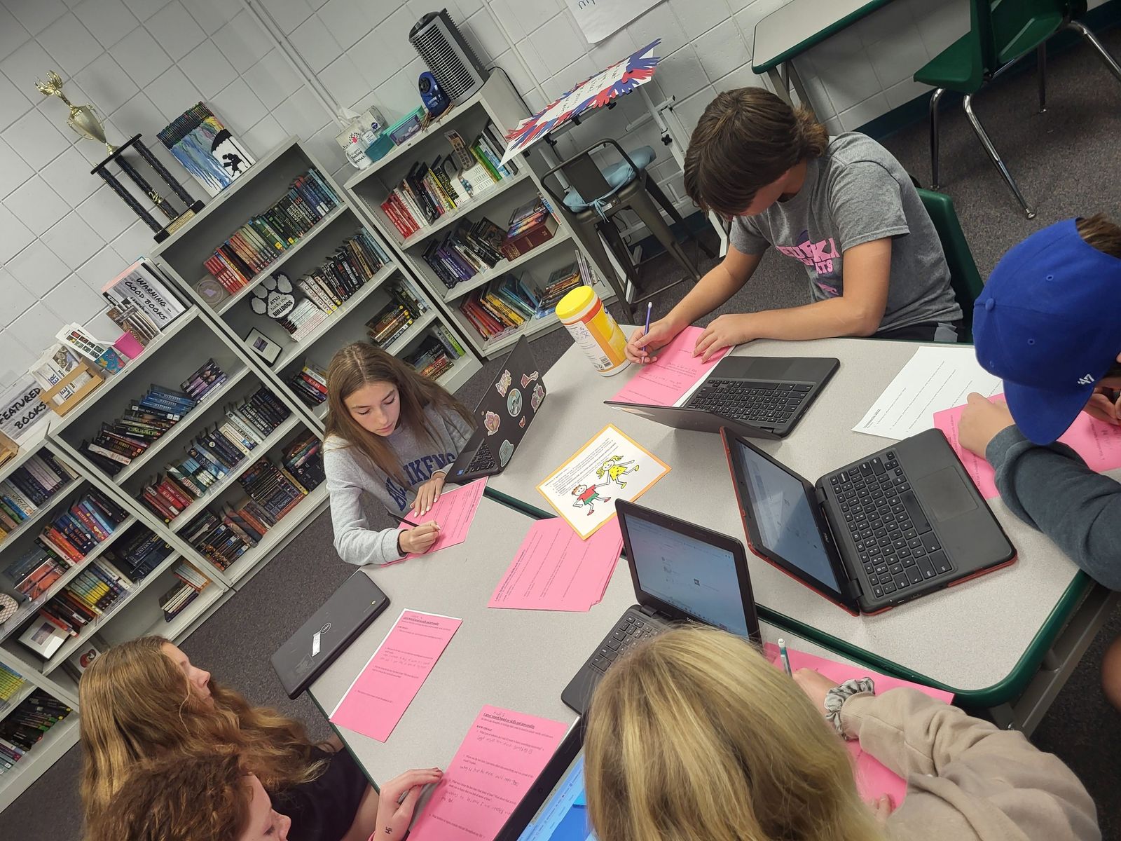 Students at classroom tables writing on laptops