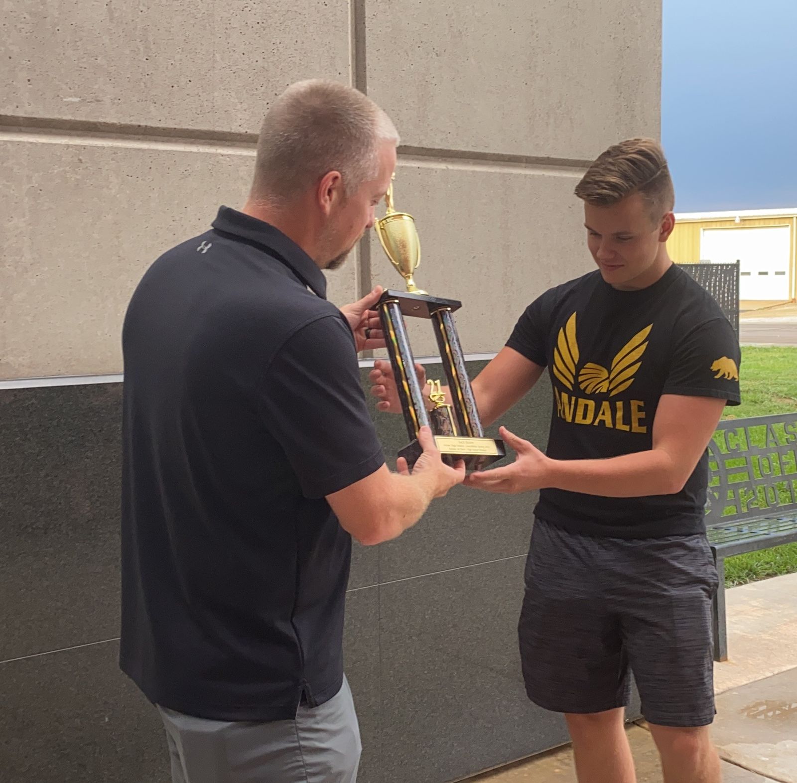 A teacher presenting a trophy to a student